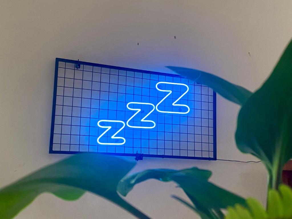玛琅Zzz Hostel Malang的墙上的蓝色 ⁇ 虹灯标志,带时钟