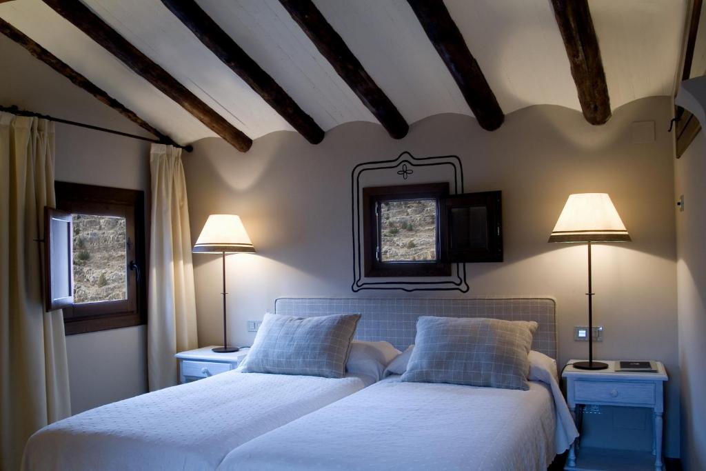 阿尔巴拉辛拉卡萨德尔提奥亚美利卡诺酒店的卧室内的两张床,配有两盏灯和电视。