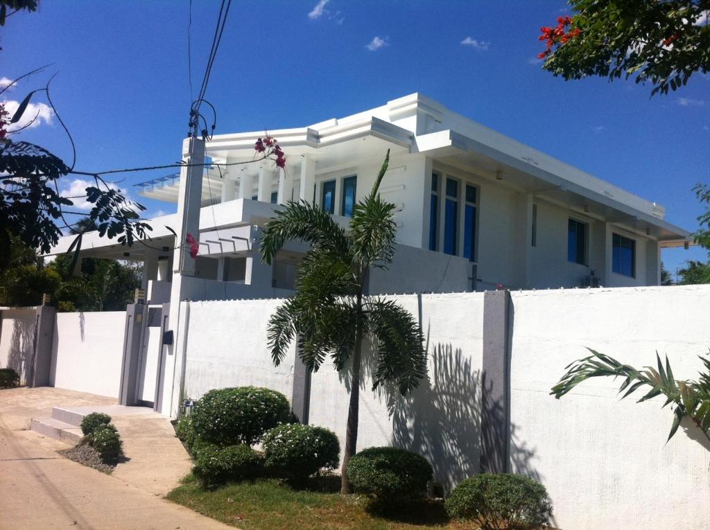 达沃市Anavada Apartment - Davao City的白色的房子,有白色的围栏和棕榈树