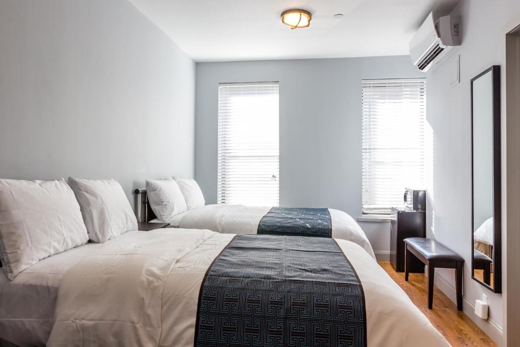 纽约公园大道北酒店的卧室设有两张床,拥有白色的墙壁和窗户。
