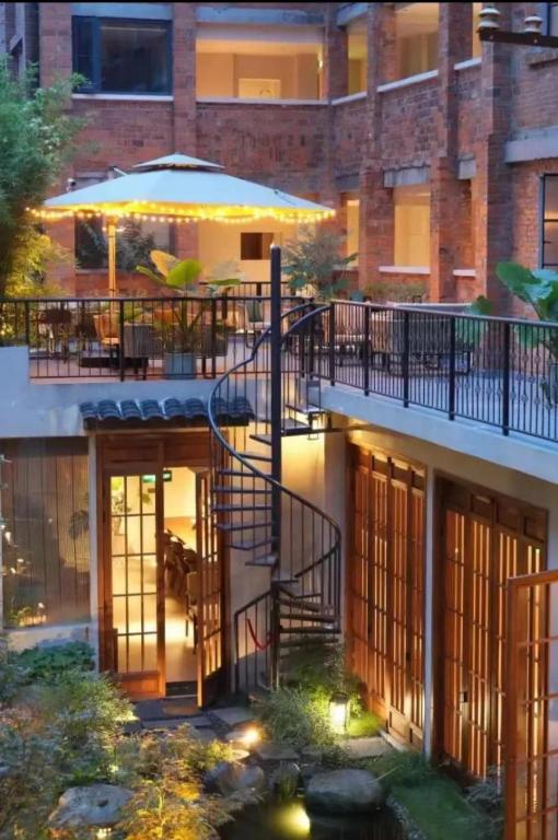 成都Chuanxing Yinli Hotel Chengdu Kuanzhai Alley Branch, with free welcome wine and afternoon tea的一座带桌子和遮阳伞的阳台的建筑
