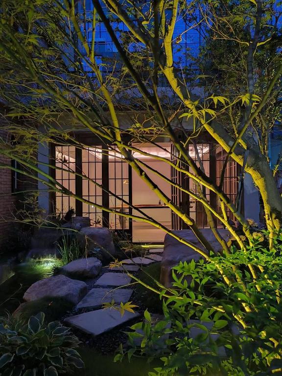成都Chuanxing Yinli Hotel Chengdu Kuanzhai Alley Branch, with free welcome wine and afternoon tea的有岩石的花园和有围栏的建筑