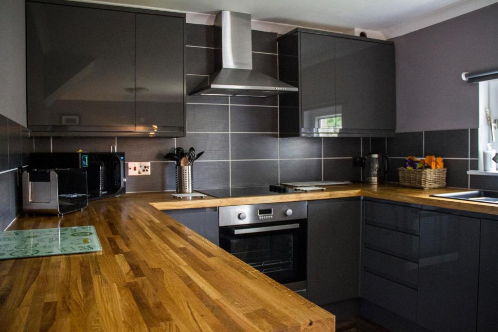 波特里家庭农庄公寓的厨房配有黑色橱柜和木制台面