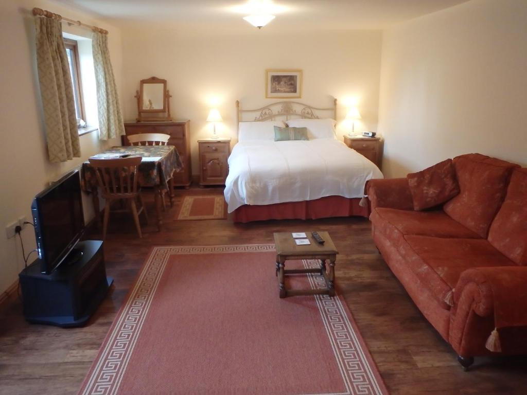 洛斯托夫特劳伦农庄庭院酒店的一间卧室配有一张床、一张沙发和一张桌子