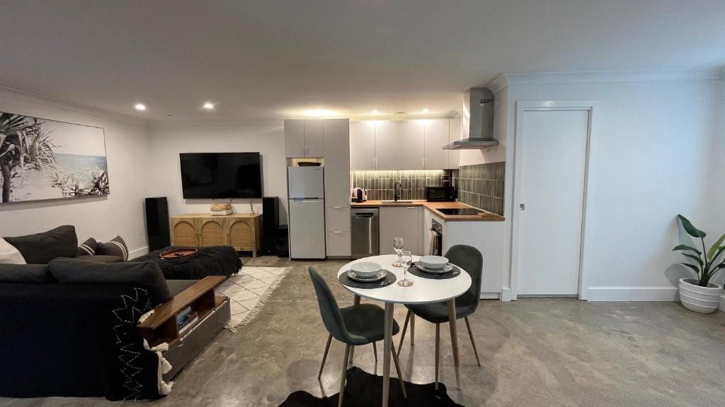 鲸滩Avalon Beach Guesthouse的客厅里有一张沙发、一张桌子和几把椅子