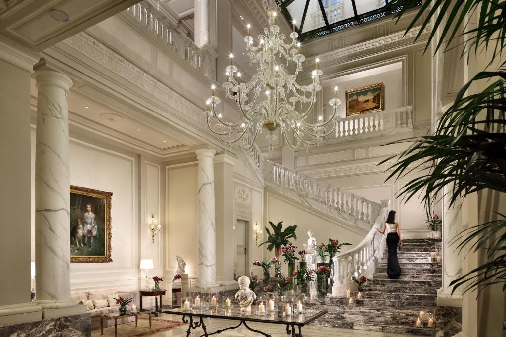 米兰LHW巴黎宫Spa大酒店的一位女士在一座带吊灯的建筑中走下楼梯