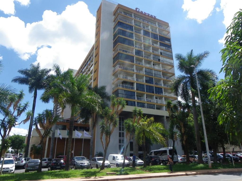巴西利亚IKA Apart Hotel的一座高大的建筑,前面有棕榈树
