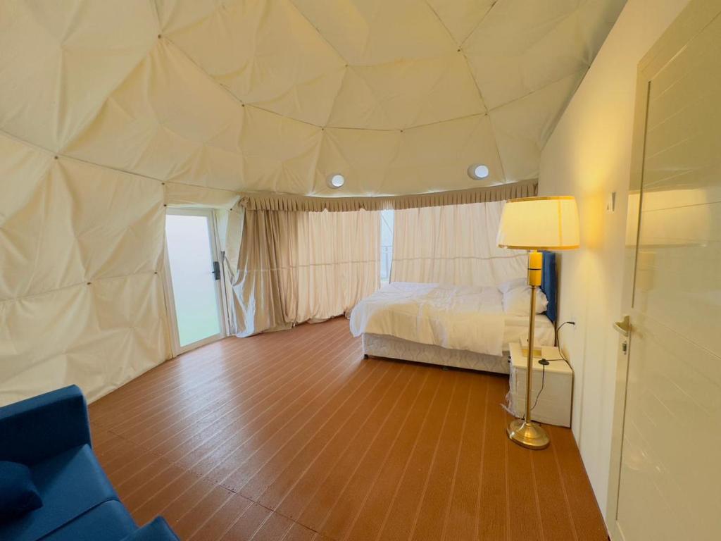 迪拜Desert Night Camping的一间卧室配有一张床和一盏灯,铺有木地板