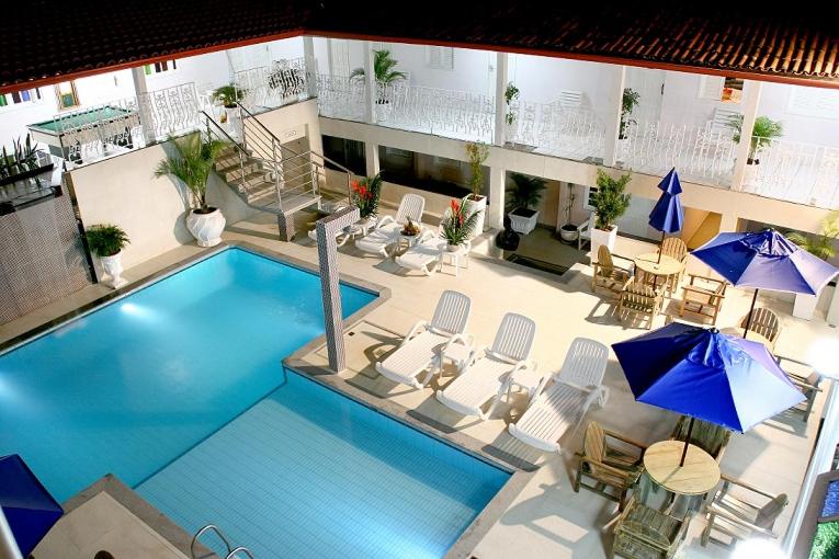 塞古罗港Ancoradouro Hotel - Centro De Porto Seguro的享有带椅子和遮阳伞的游泳池的上方景色