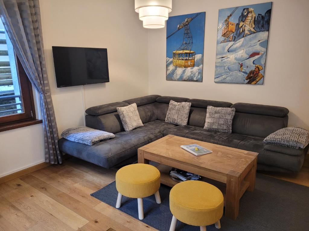 夏蒙尼-勃朗峰Cham&#39;Heart, 4-star apartments in Chamonix centre with free private parking的客厅配有沙发、桌子和2把凳子
