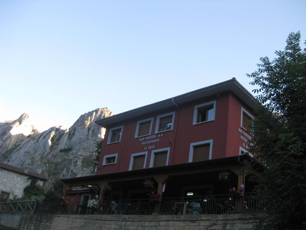 TielveHostal el Duje的一座红色的建筑,背景是一座山