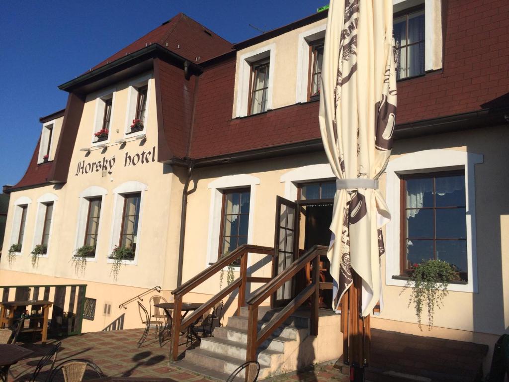 PřimdaHorský Hotel Kolowrat的白色的建筑,有棕色的屋顶和楼梯
