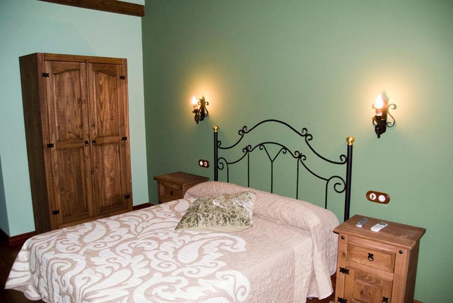 Villar de Plasencia萨尔瓦多林孔德尔比利亚尔酒店的卧室配有一张床,墙上有两盏灯