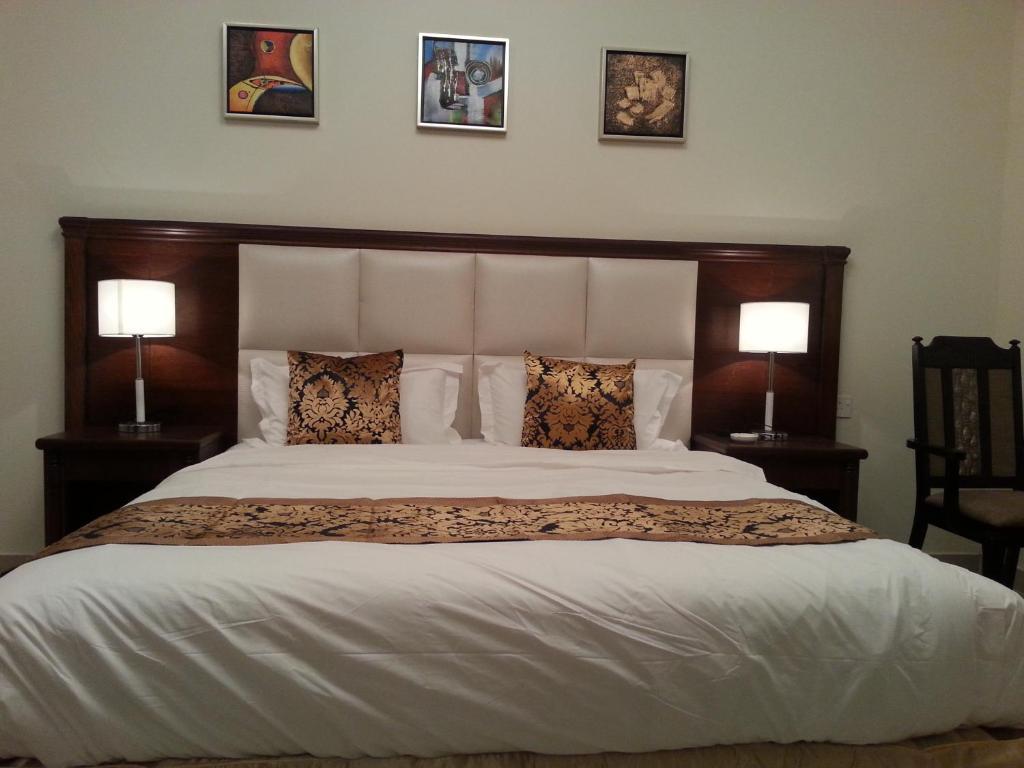 塞卡凯Lara Al Jawf Hotel Apartments的一间卧室配有一张大床和两盏灯