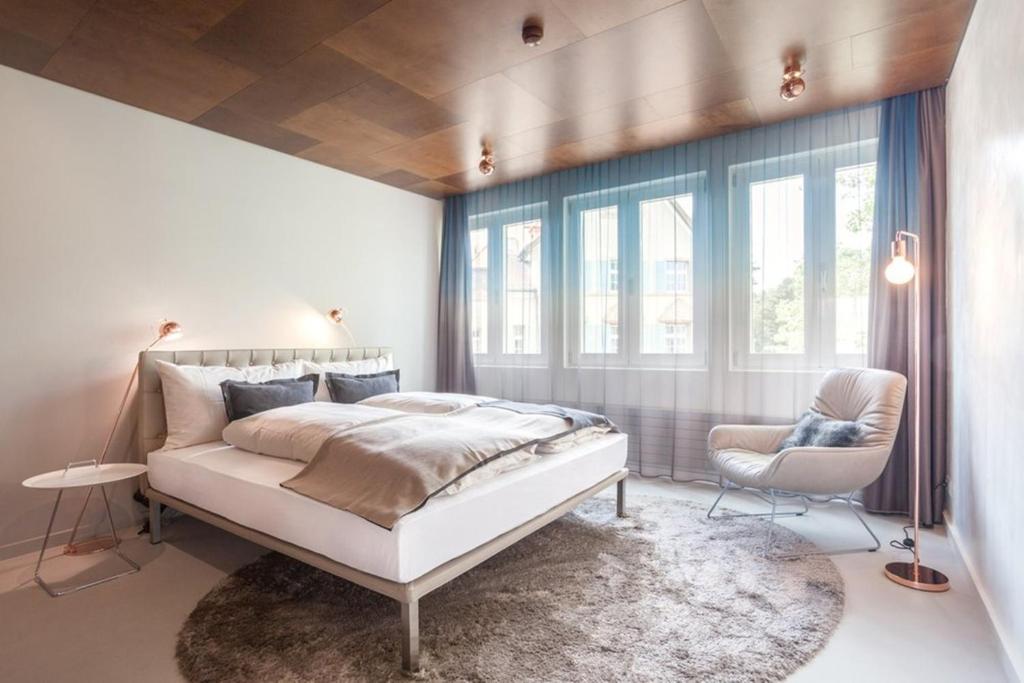 苏黎世EMA之家套房酒店的一间卧室配有一张床、一把椅子和窗户。