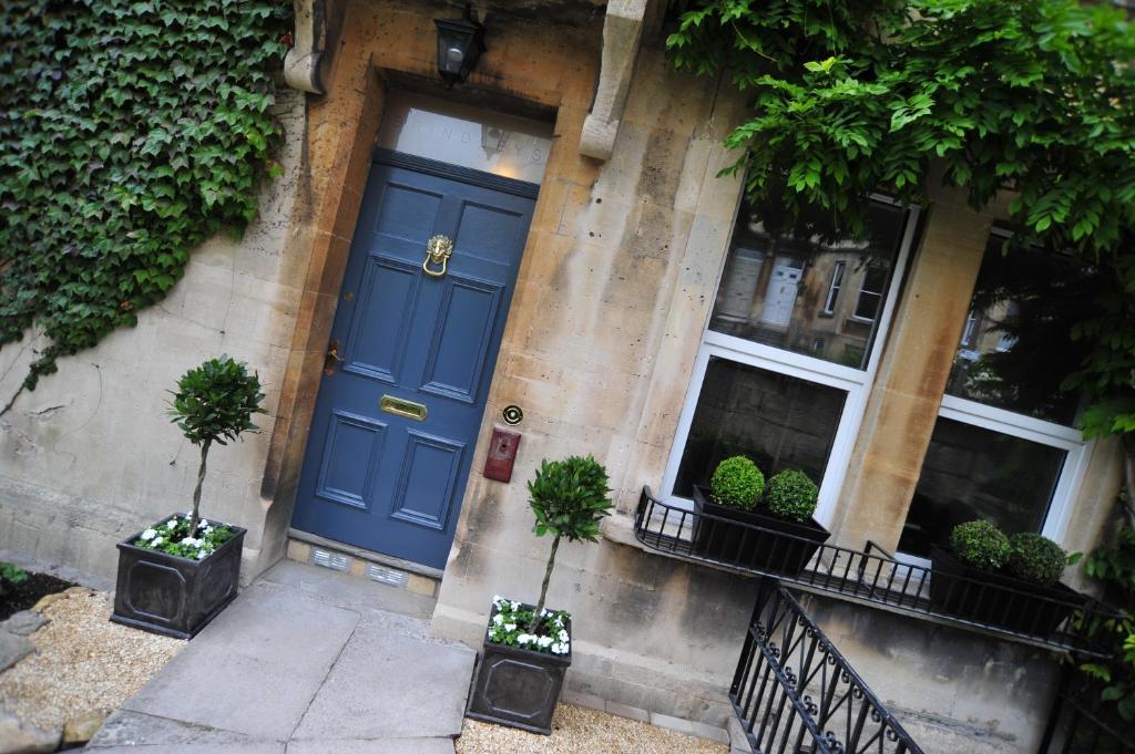 巴斯布瑞德雷酒店的一座种植盆栽植物的建筑的一边,一扇蓝色的门