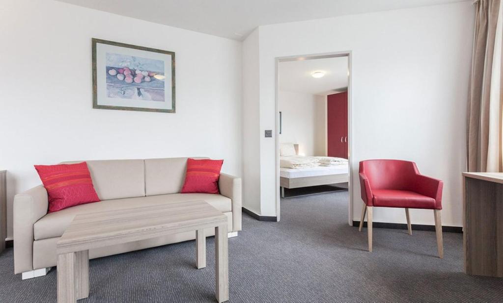 苏黎世EMA House Serviced Apartments Aussersihl的带沙发和红色椅子的客厅