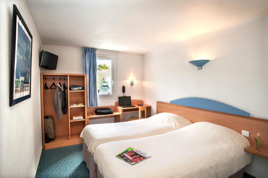 圣弗卢尔Brit Hotel Essentiel Saint-Flour的酒店客房设有两张床和窗户。