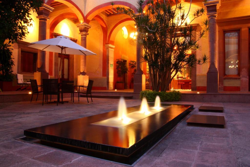 克雷塔罗Casona de la Republica Hotel Boutique & SPA的一座带遮阳伞的建筑的庭院中的喷泉