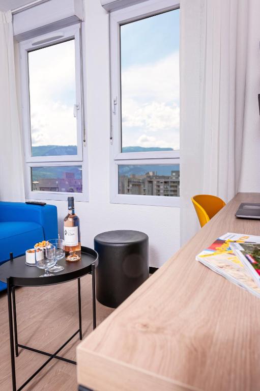 格勒诺布尔Apparthotel Le Hüb Grenoble的一间设有两张桌子和两个窗户的房间