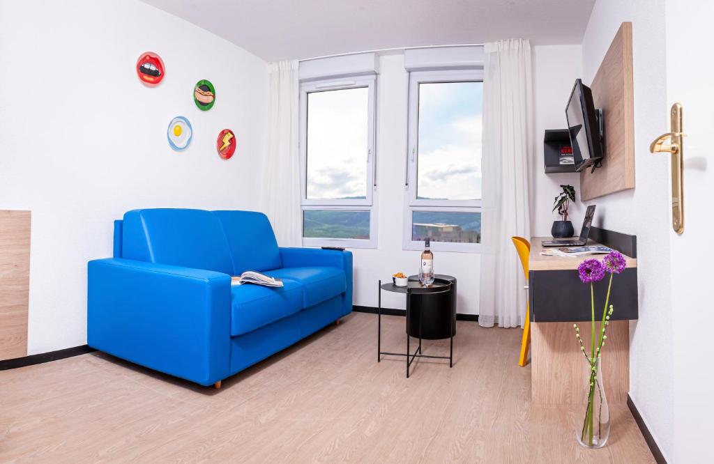 格勒诺布尔Apparthotel Le Hüb Grenoble的客厅里有一张蓝色的沙发和一张桌子