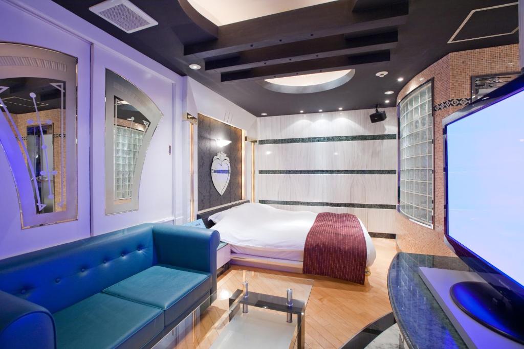 东京新宿歌舞伎町J-MEX酒店及水疗中心（仅限成人入住） 的客房设有床、沙发和电视。
