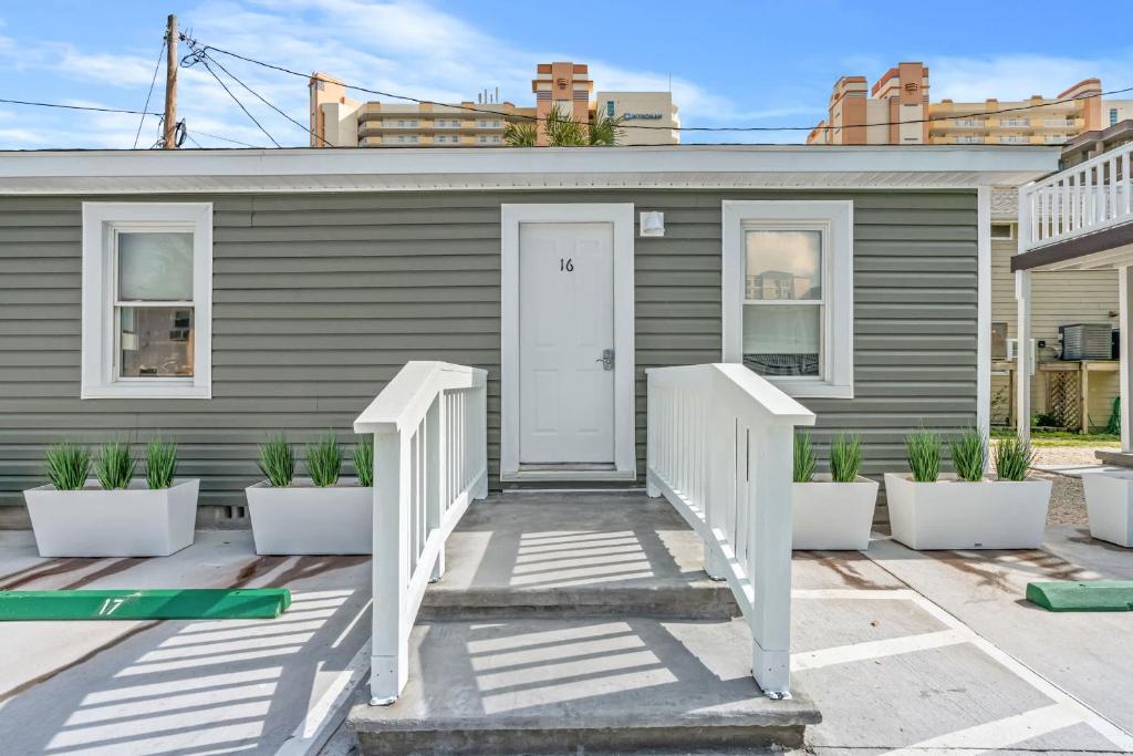 默特尔比奇Cozy Beachside Bungalow Studio Ideal for Couples的白色门和一些植物的灰色房子
