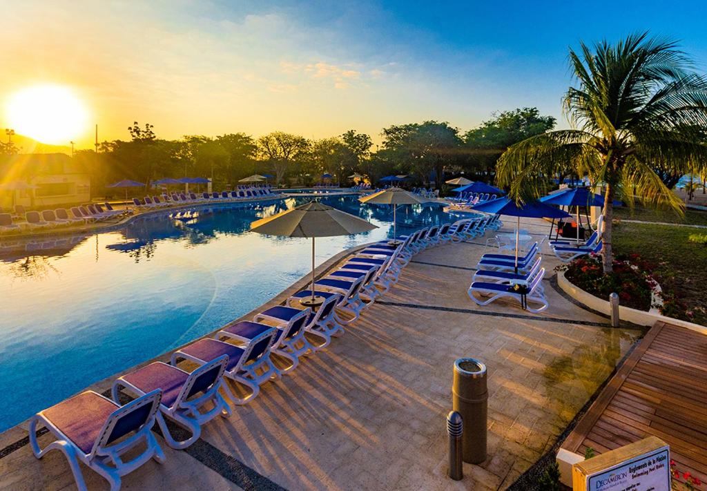 蒙特鲁伊斯英迪戈得可麦仑皇家酒店 - 全包的一个带椅子和遮阳伞的游泳池,享有日落美景