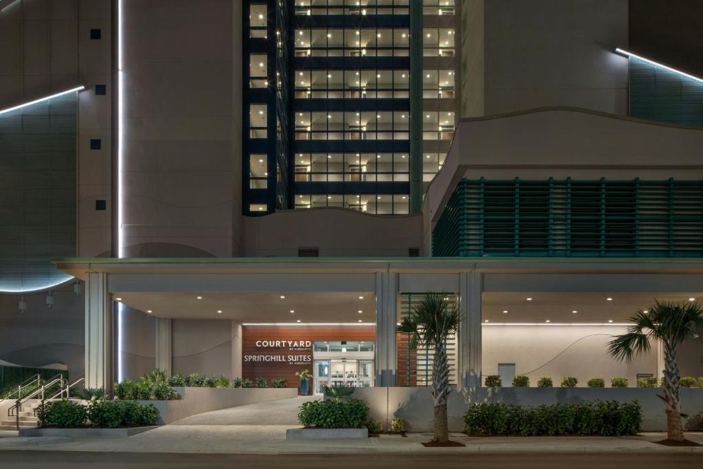默特尔比奇Courtyard by Marriott Myrtle Beach Oceanfront的一座棕榈树在晚上的建筑