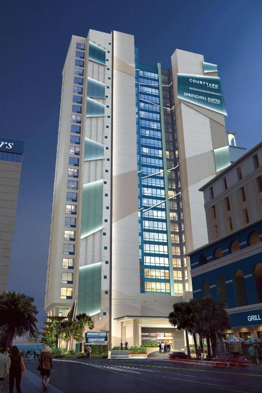 默特尔比奇Courtyard by Marriott Myrtle Beach Oceanfront的一座大楼，前面有人走动