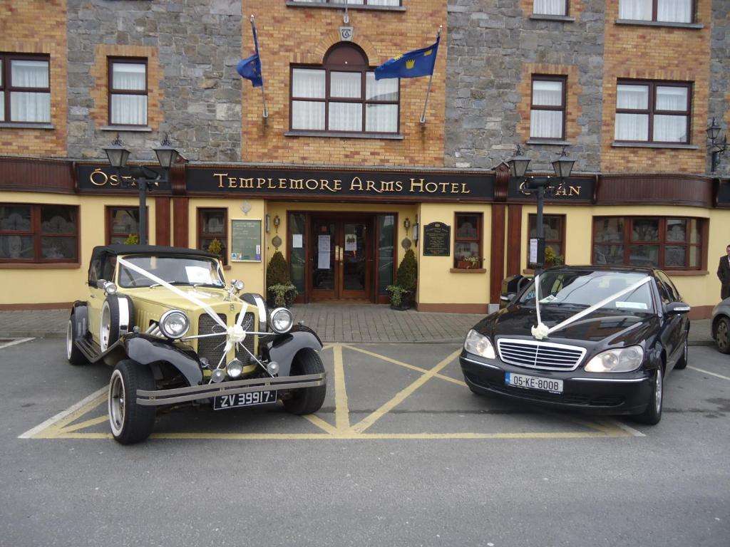 坦普尔莫尔Templemore Arms Hotel的两辆汽车停在大楼前的停车场