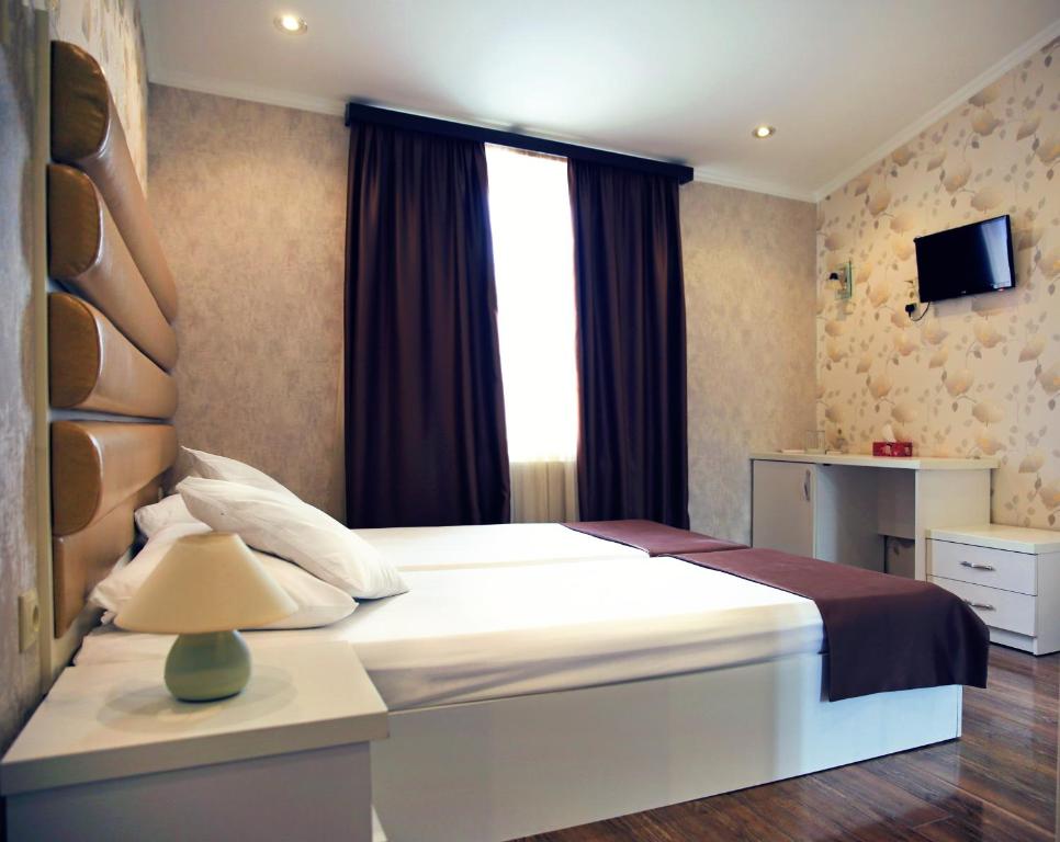 第比利斯朗多酒店的一间卧室设有一张大床和窗户