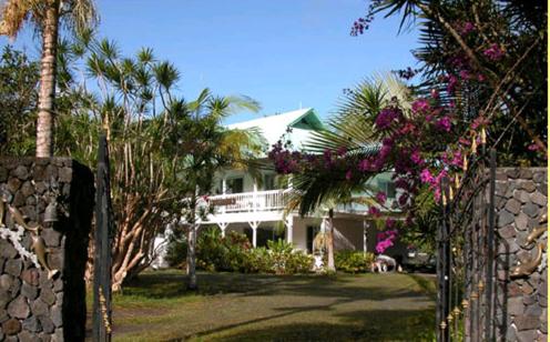 帕霍阿热带熔岩树美景酒店的一座白色的房子,种植了棕榈树,设有围栏