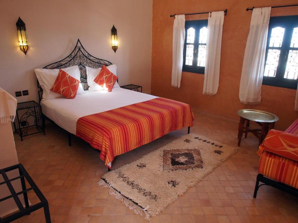 瓦尔扎扎特布舍多摩洛哥传统庭院住宅的一间卧室设有一张大床,拥有橙色的墙壁和窗户。