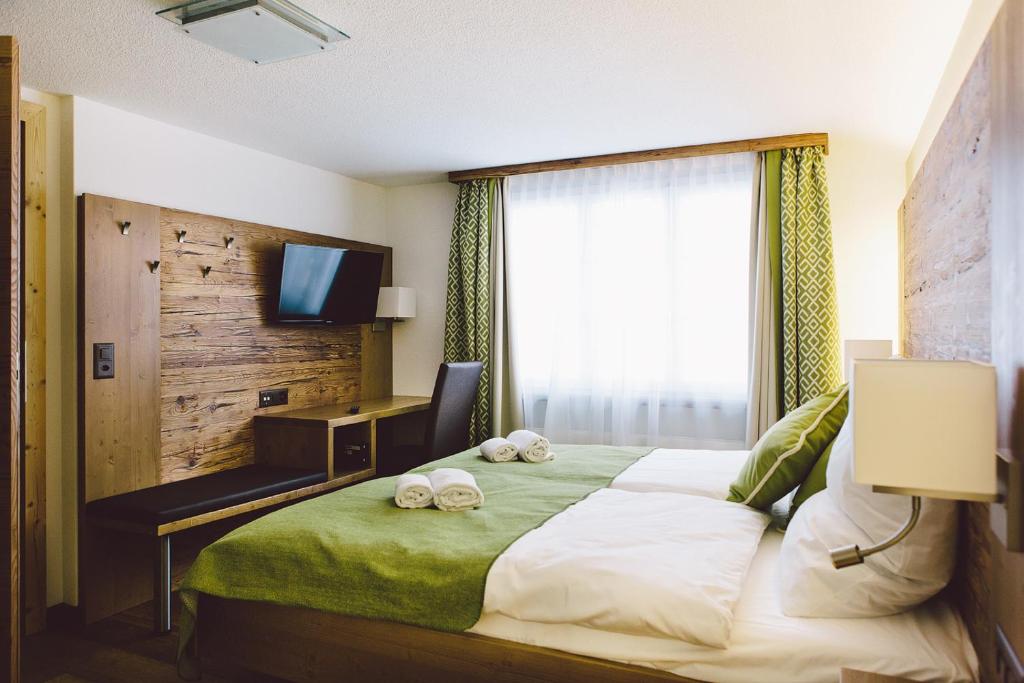 安德马特Hotel & Restaurant Zum Schwarzen Bären的一间卧室配有一张带电视的床和2个拖鞋。