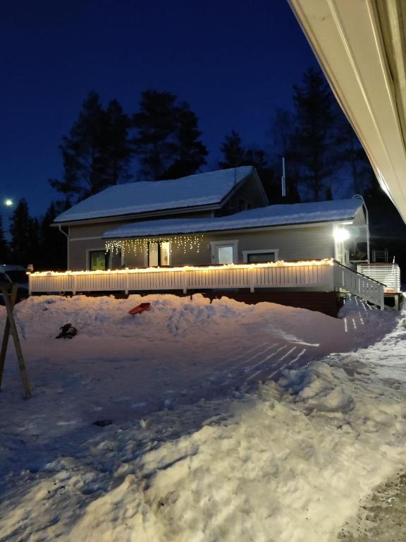 KarunkiHuruvaarantien talo的夜晚雪中灯火通明的房子