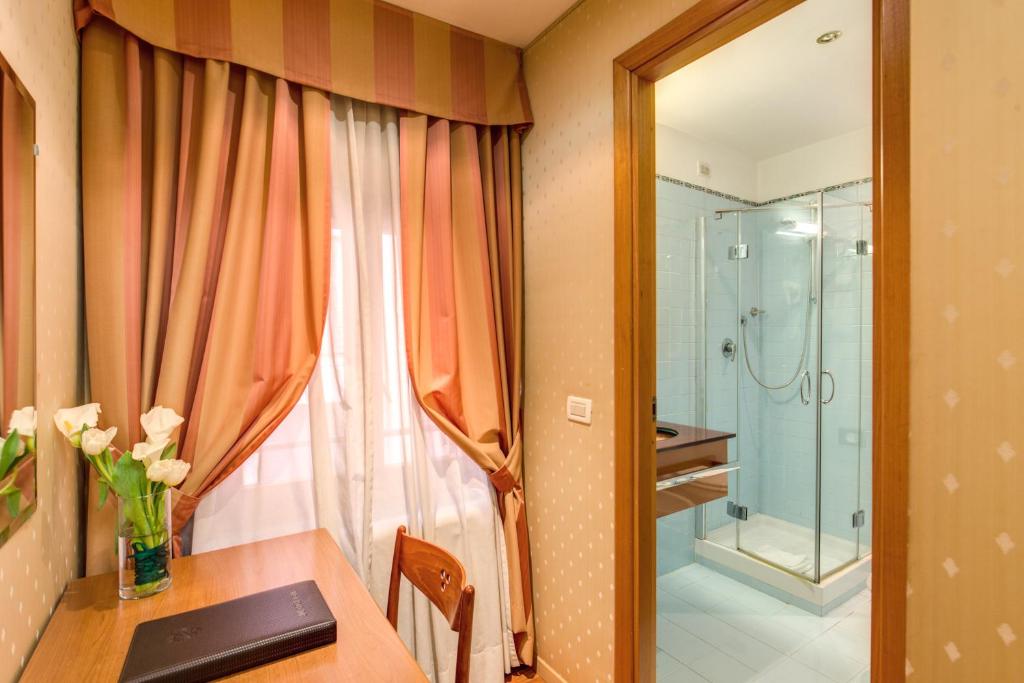 罗马花团锦簇酒店的一间带桌子和玻璃淋浴间的浴室