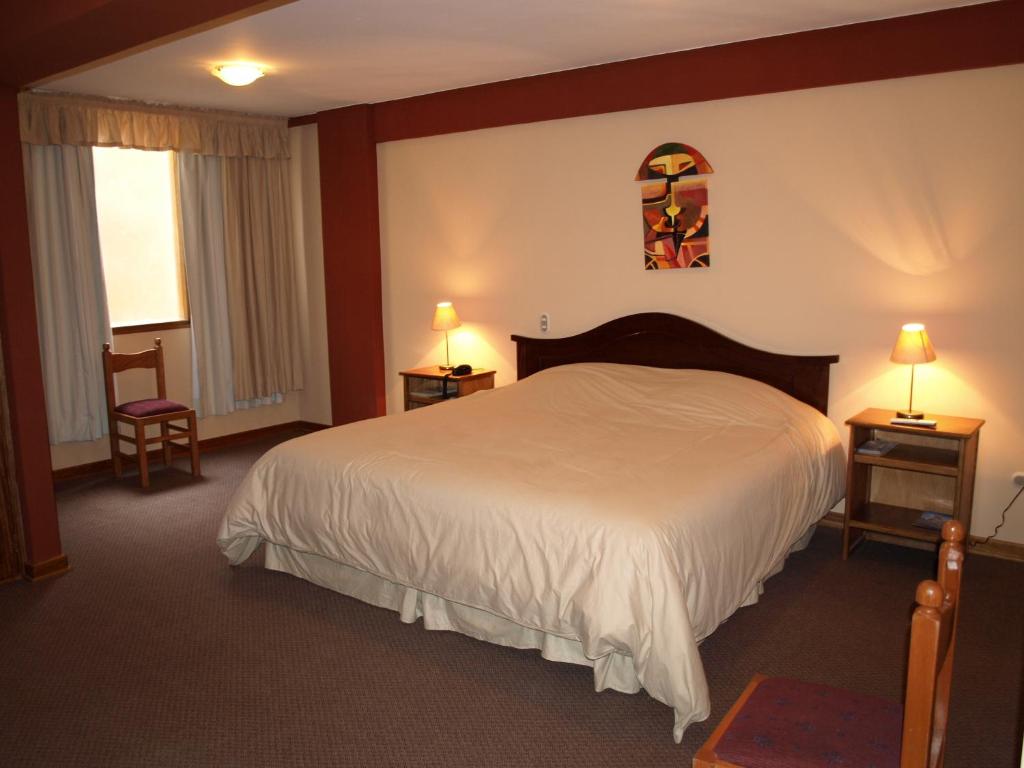 普诺奎尔他尼酒店的一间卧室配有一张床、两张桌子和两盏灯。