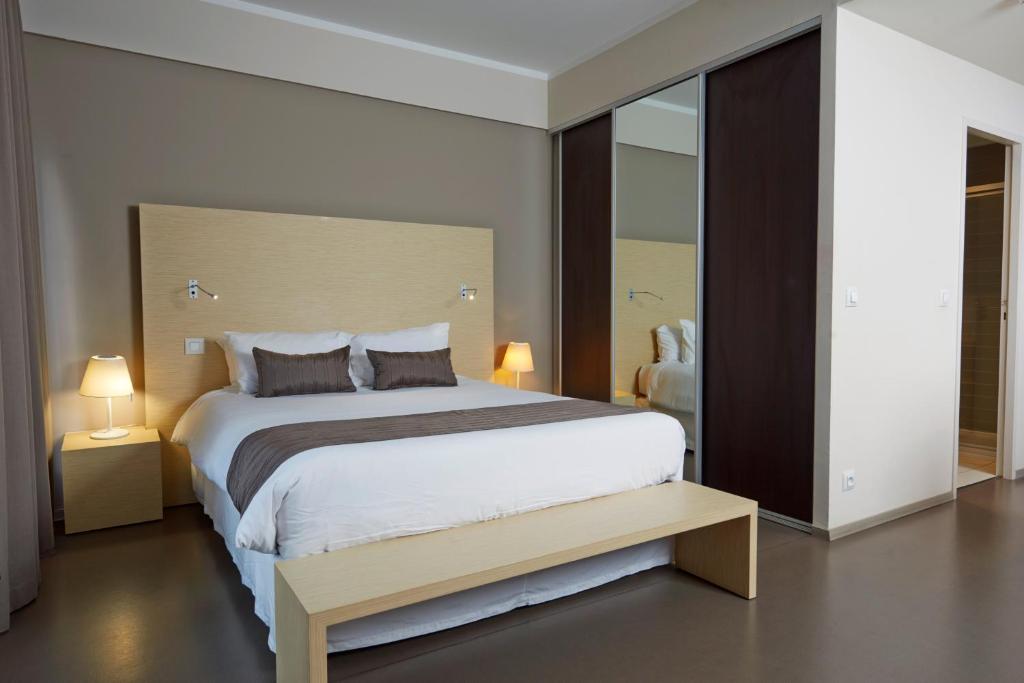 努美阿中心酒店的一间卧室设有一张大床和一个大镜子