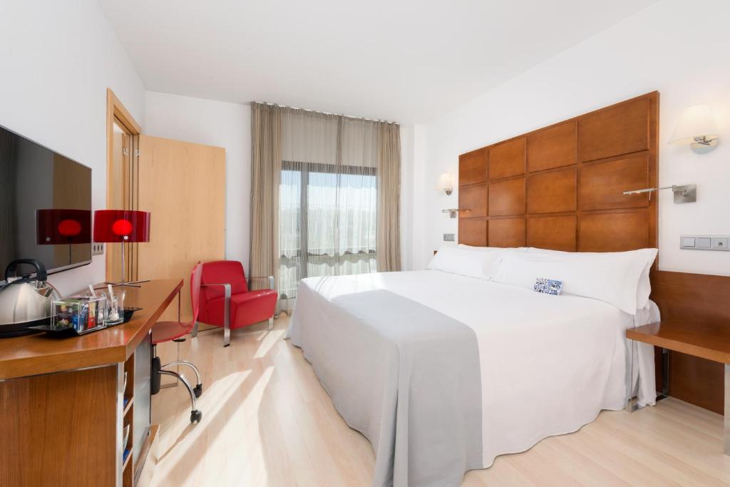 萨拉戈萨Hotel Zentral Ave的酒店客房设有一张白色大床和一张书桌