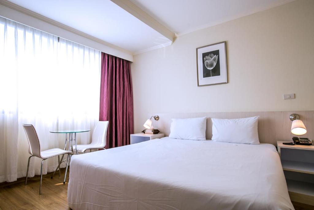 曼谷伊丽莎白酒店的酒店客房设有一张白色大床和一张桌子。
