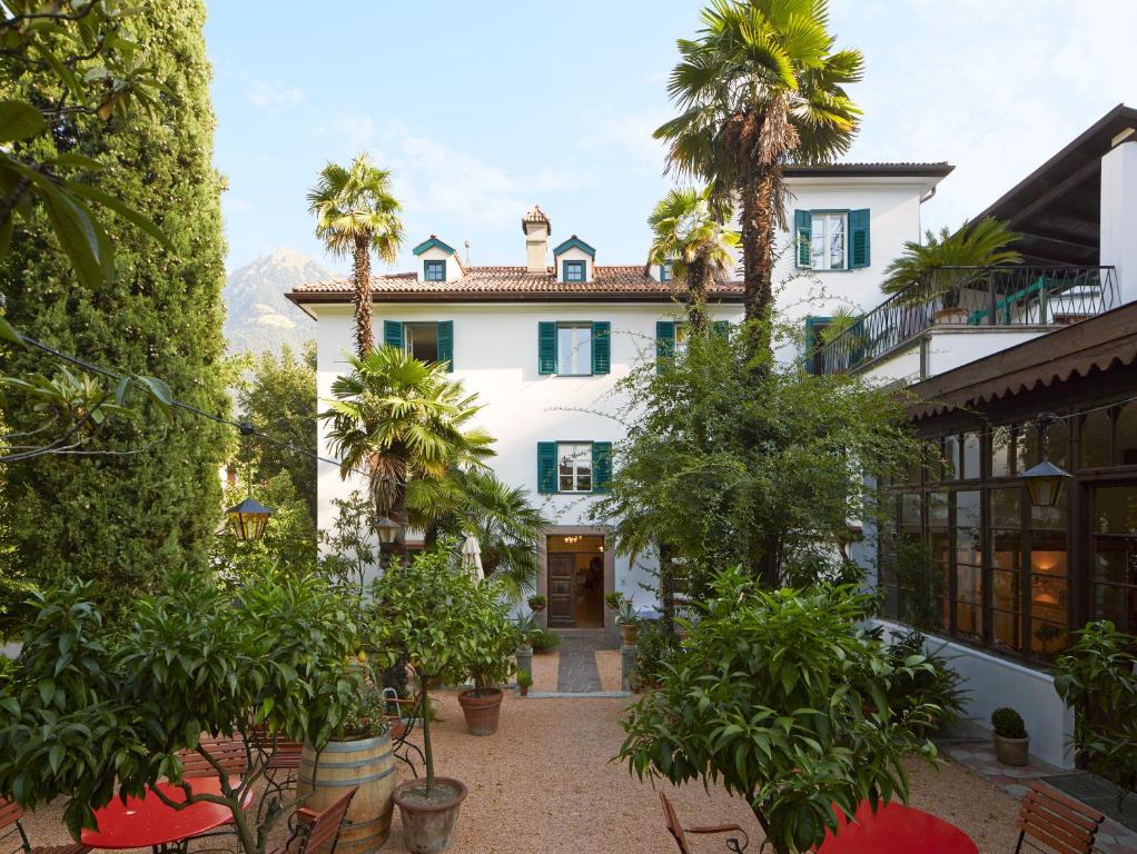 梅拉诺奥特曼古特套房及早餐酒店的享有棕榈树白色房屋的外部景色