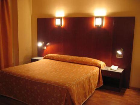 萨莫拉多纳沃卡酒店的一间卧室配有一张带两张桌子和两个灯的床