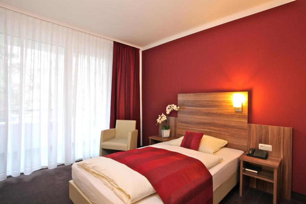 巴德索登陶努斯巴特索登森林酒店的一间卧室配有一张红色墙壁的床