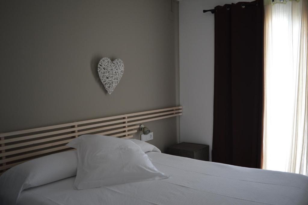 卡达克斯诺艾斯特乐斯酒店的卧室配有白色床,墙上有心