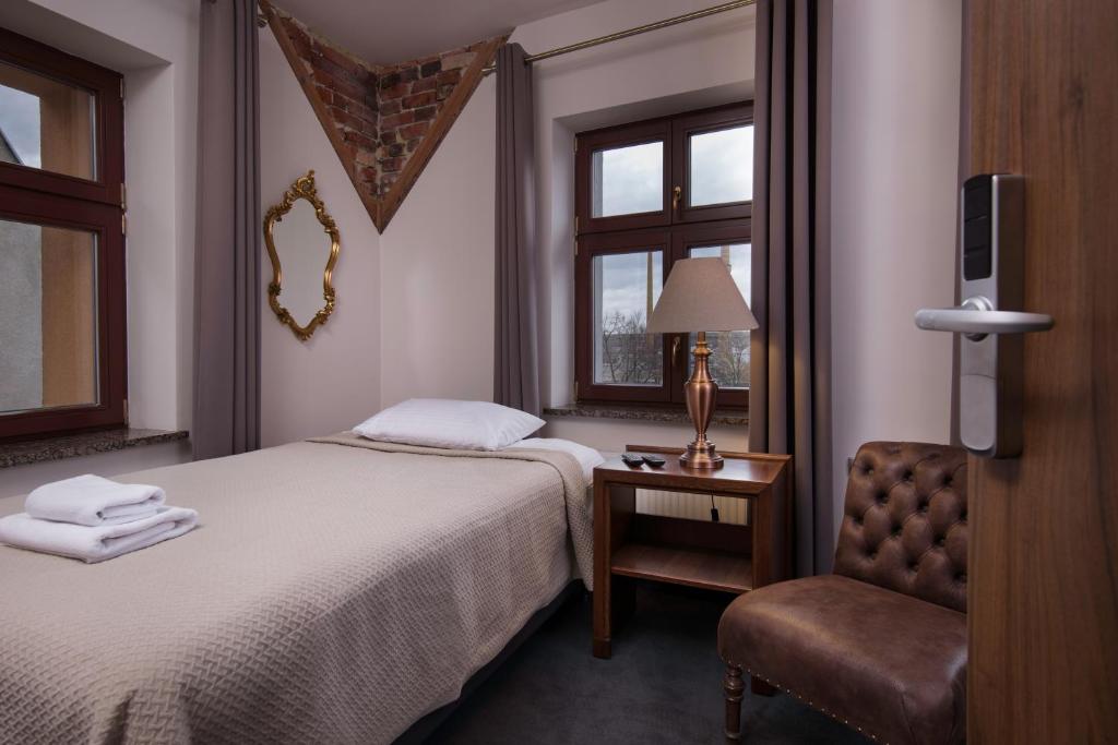 绿山城Hotel Retro B.A. Zientarski的配有一张床和一把椅子的酒店客房