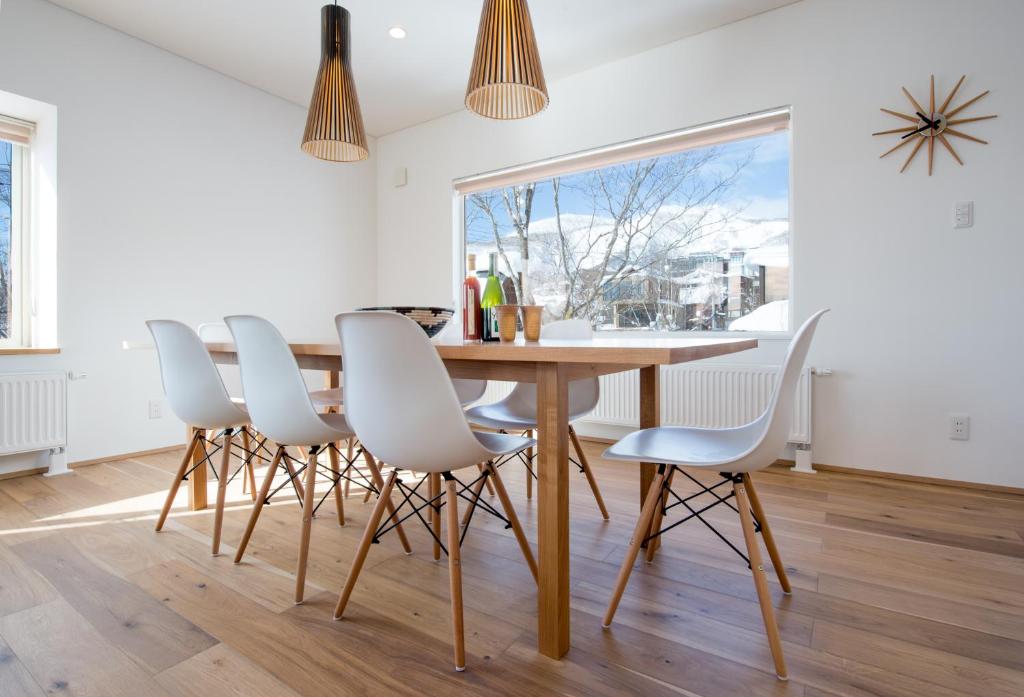 二世古优苏基小木屋的一间带木桌和白色椅子的用餐室