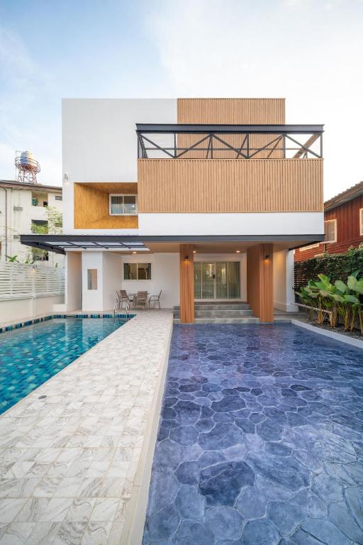 清迈Baan San sook Pool Villa at Nimman的一栋楼前有游泳池的房子