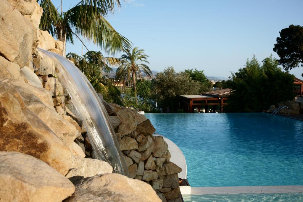 托雷法罗摩根娜别墅度假村 的一座游泳池,旁边是岩石墙,设有水滑梯