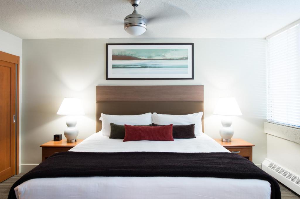 温哥华UBC西海岸套房公寓式酒店的一间卧室配有一张带两盏灯的大型白色床。